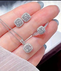 Diamond jewelry set including necklace and earrings on a hand.