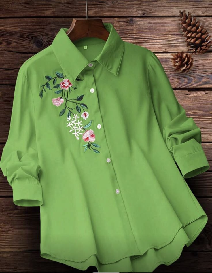 Green blouse with floral embroidery on a wooden background
