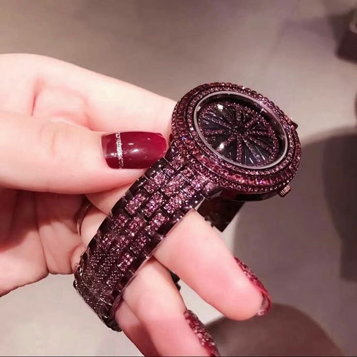 Hand holding a glittery purple watch with a blurred background