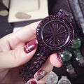 Hand holding a purple glittery watch with a blurred background