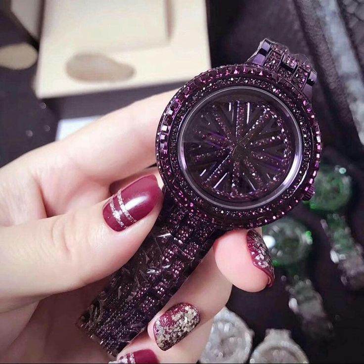 Hand holding a purple glittery watch with a blurred background