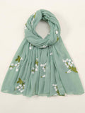 Light green scarf with floral embroidery on a white background