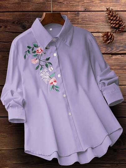 Light purple shirt with floral embroidery on a wooden surface