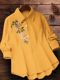 Light yellow shirt with floral embroidery on a wooden surface