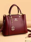 Maroon handbag with a brand logo on a beige background