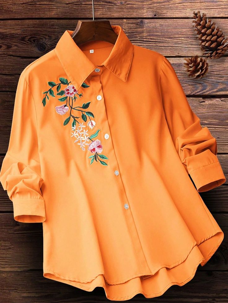 Orange shirt with floral embroidery on a wooden surface