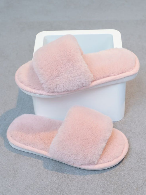 Pair of pink fluffy slippers on a light gray background