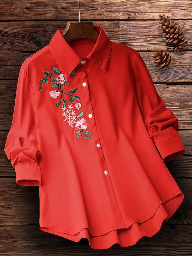 Red blouse with floral embroidery on a wooden surface