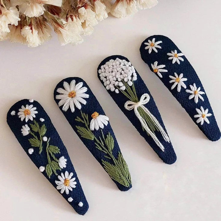 Set of four navy blue hair clips with floral designs on a light background