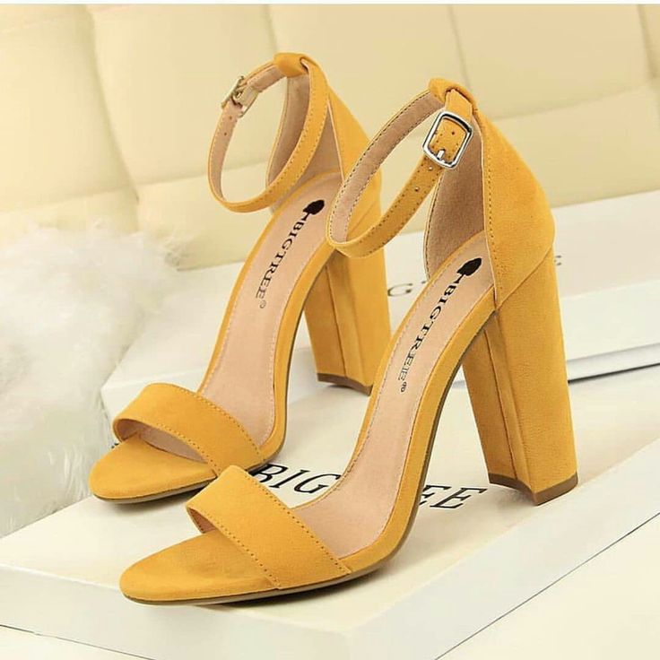 Yellow high-heeled sandals on a white surface with a beige background